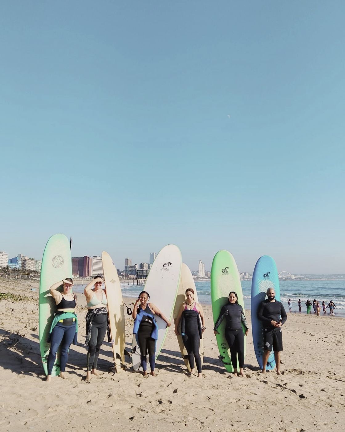A Be the Calm group with their surfboards on the beach